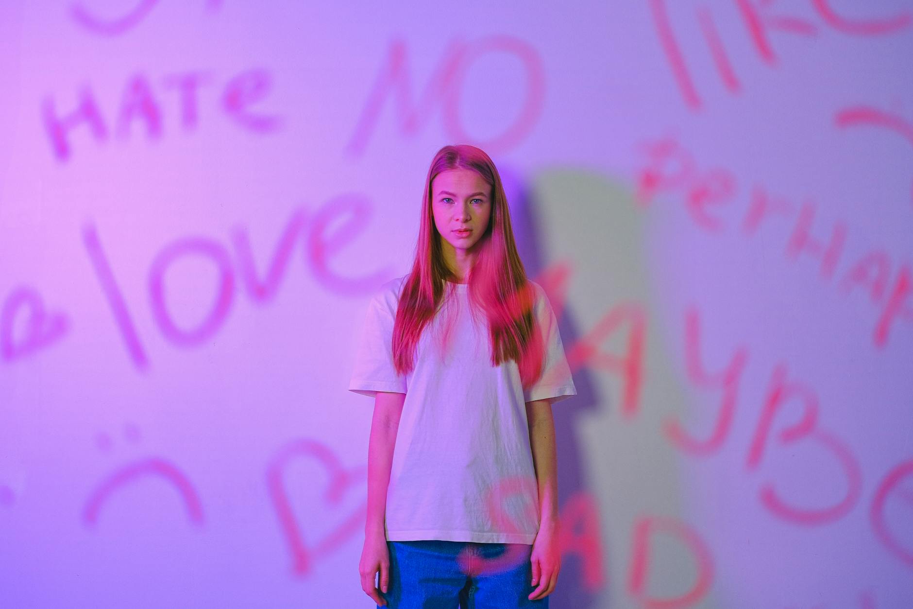 Expressive studio portrait of a teenager with graffiti, capturing emotion and mood with a pink hue. - express complex emotions