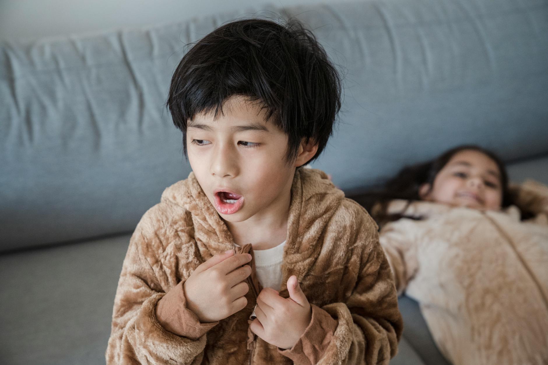 Young boy and girl in cozy animal onesies sitting on a couch, creating a playful home environment. - family guy sibling rivalry