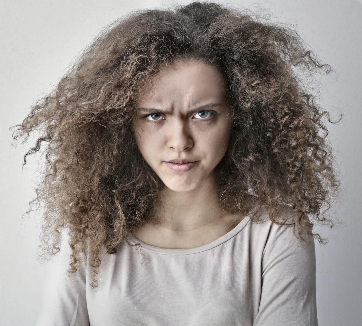 Portrait of a woman with curly hair showing an angry facial expression. Ideal for emotion-based content. - free anger management
