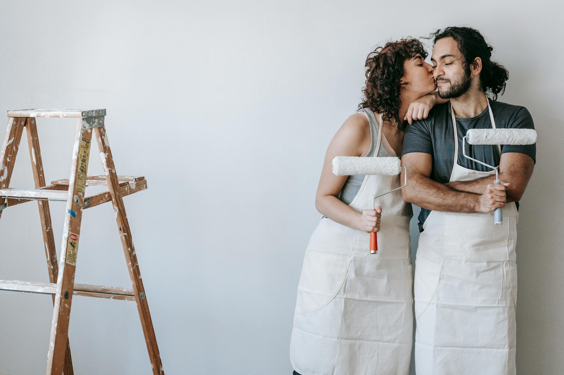 A loving couple takes a break from painting to share a sweet kiss in their newly renovated home. - future goals couple