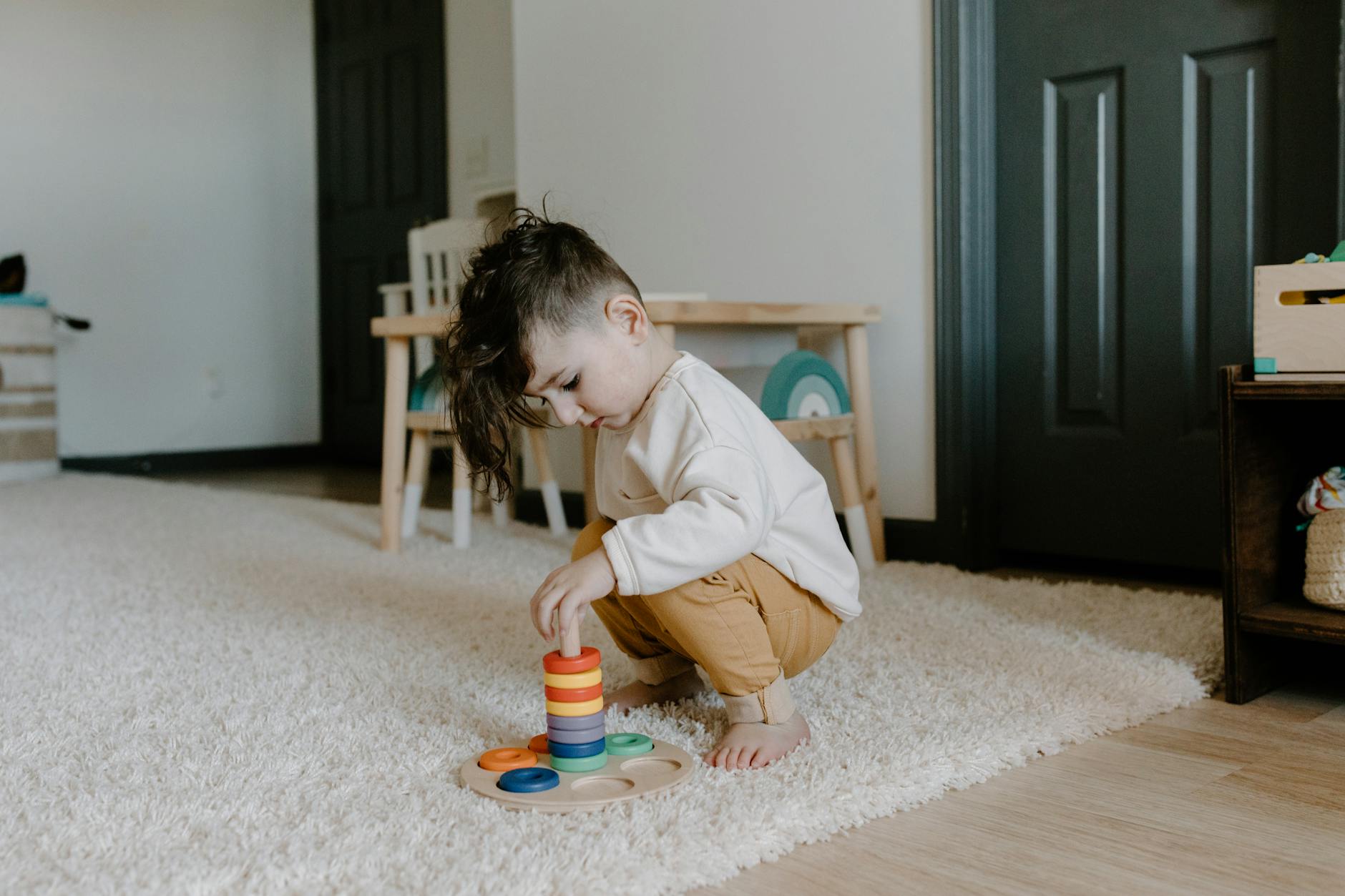 Young child engaging with colorful educational toy in cozy indoor setting. - independent play toddler