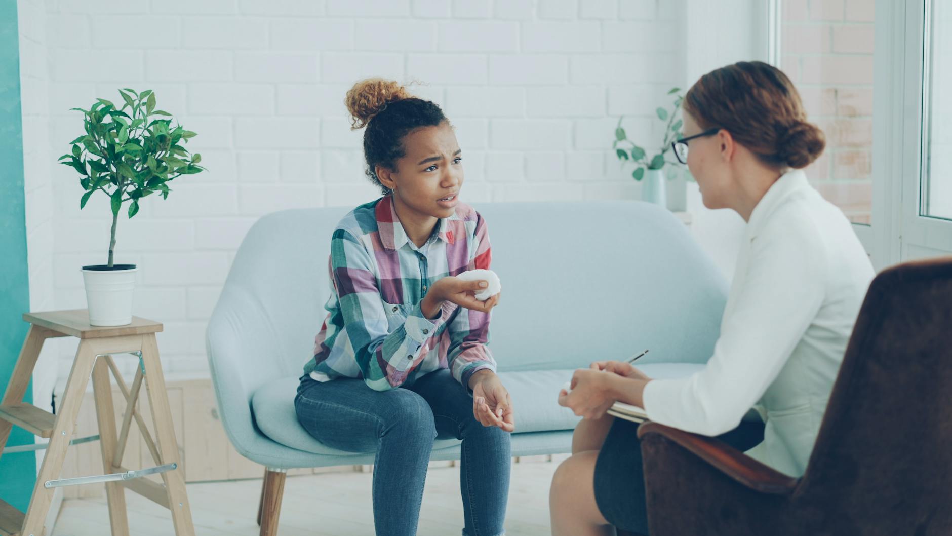 A young woman in discussion with a counselor during a session. Modern, bright office setting. - mental health decluttering