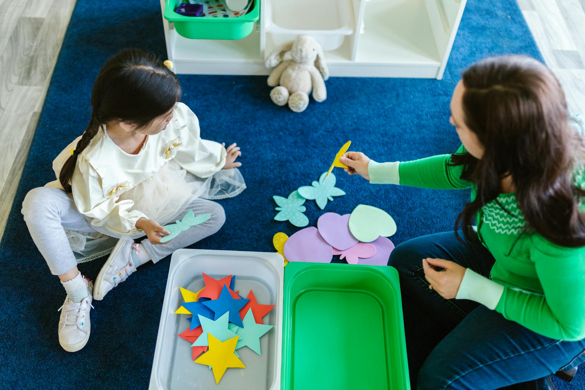 Child and adult engaging in educational play with paper cutouts indoors. - preschool spring activities