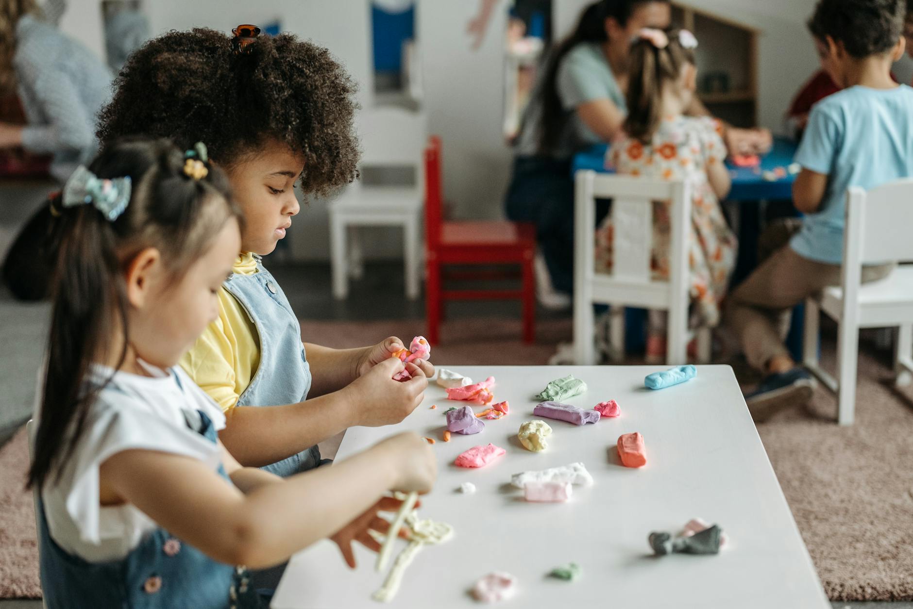 Kids at a preschool table playing with colorful clay, fostering creativity and teamwork. - preschool spring changes