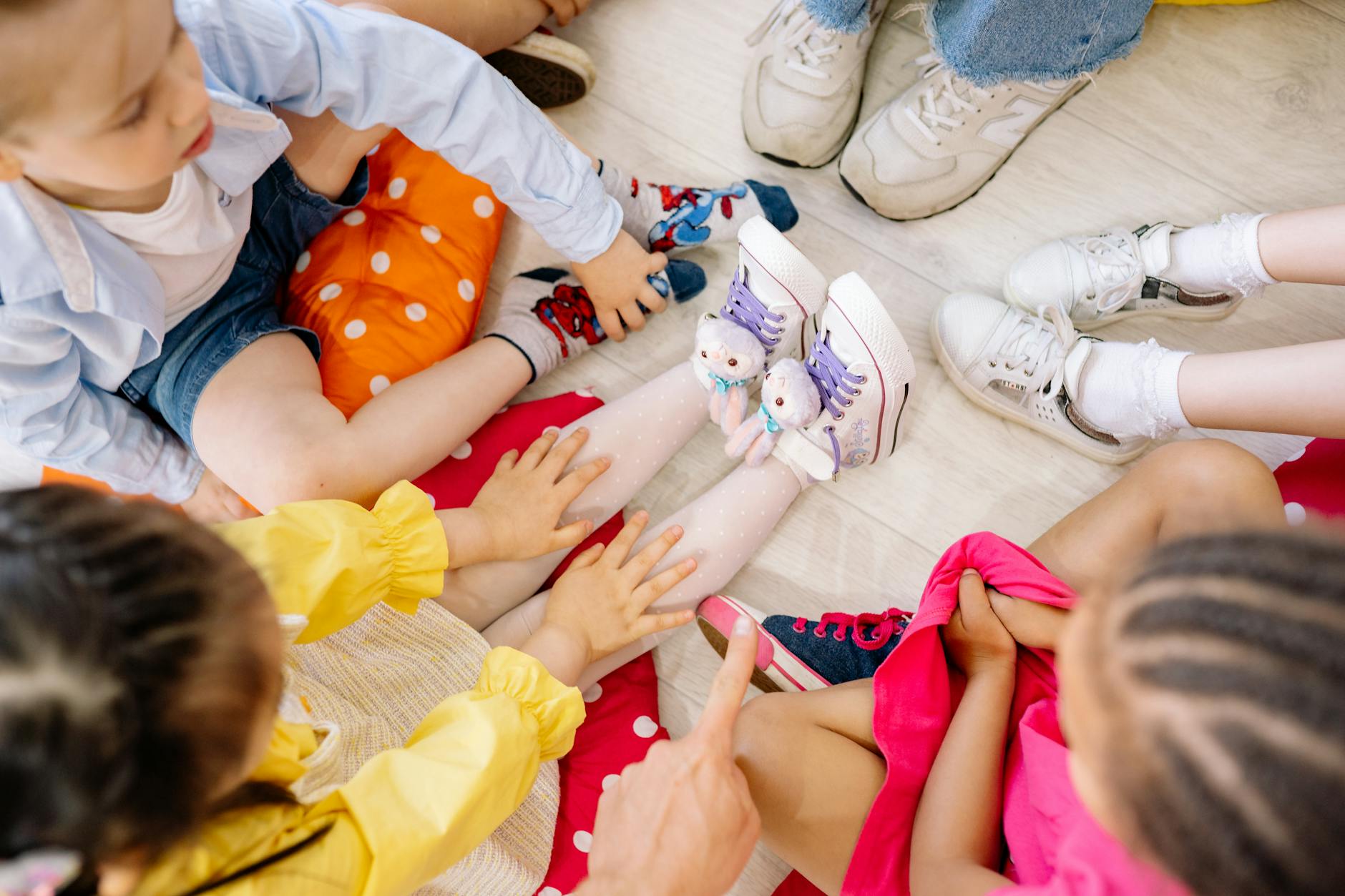 Children sitting in a circle on a wooden floor, engaging in fun indoor activities. - preschooler spring play