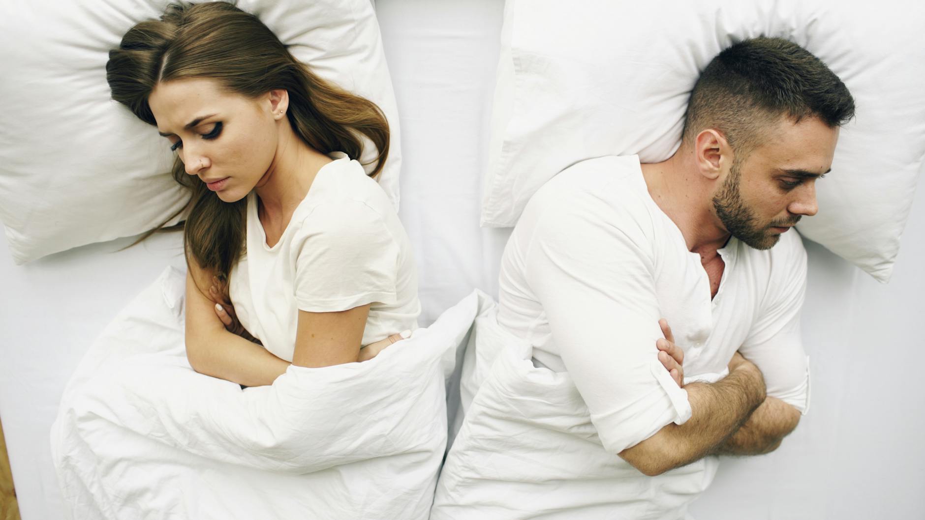 A couple lying in bed facing away, expressions of discontent. - relationship resentment