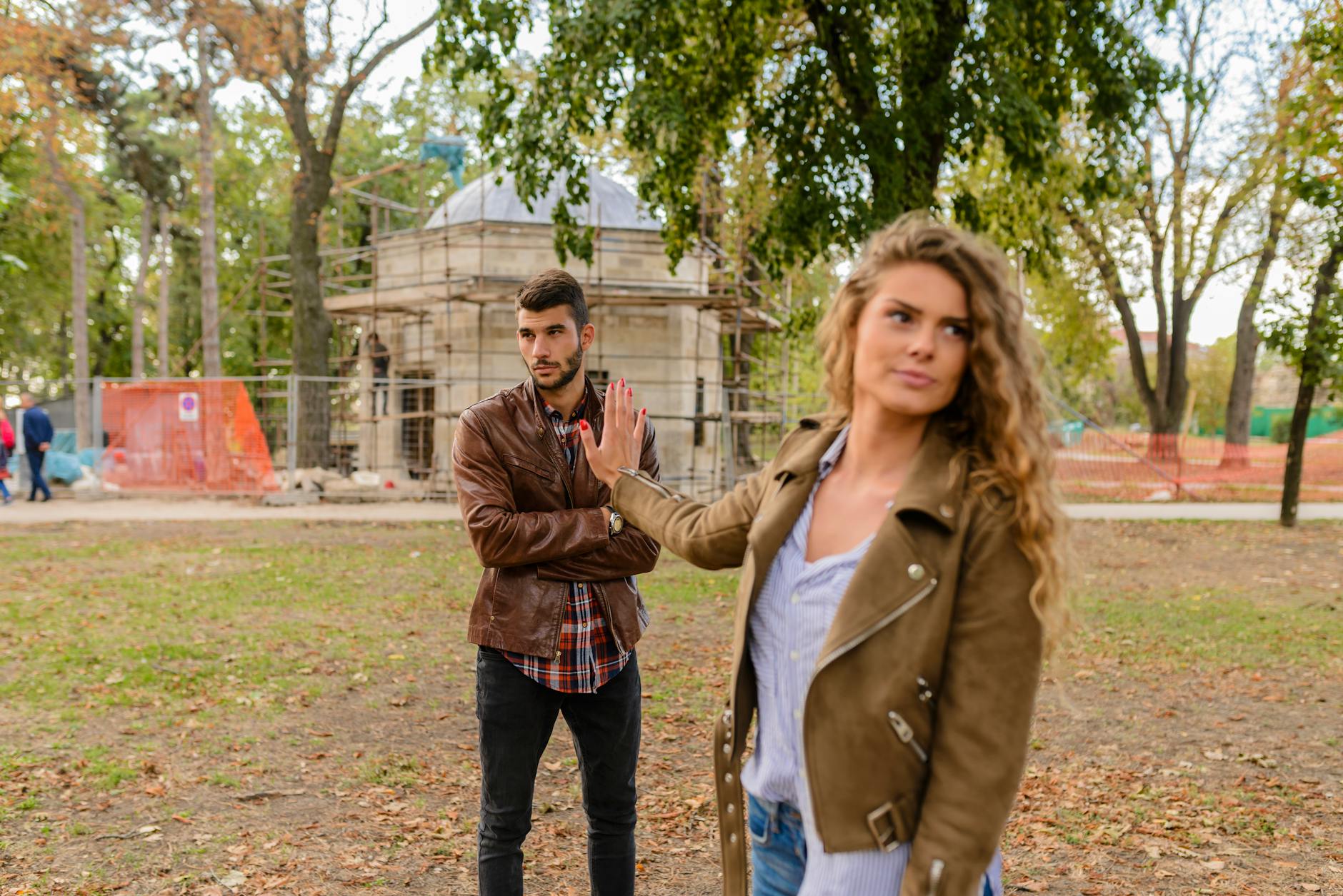 A couple faces disagreement outdoors in a park setting showcasing emotional expressions. - relationship resentment