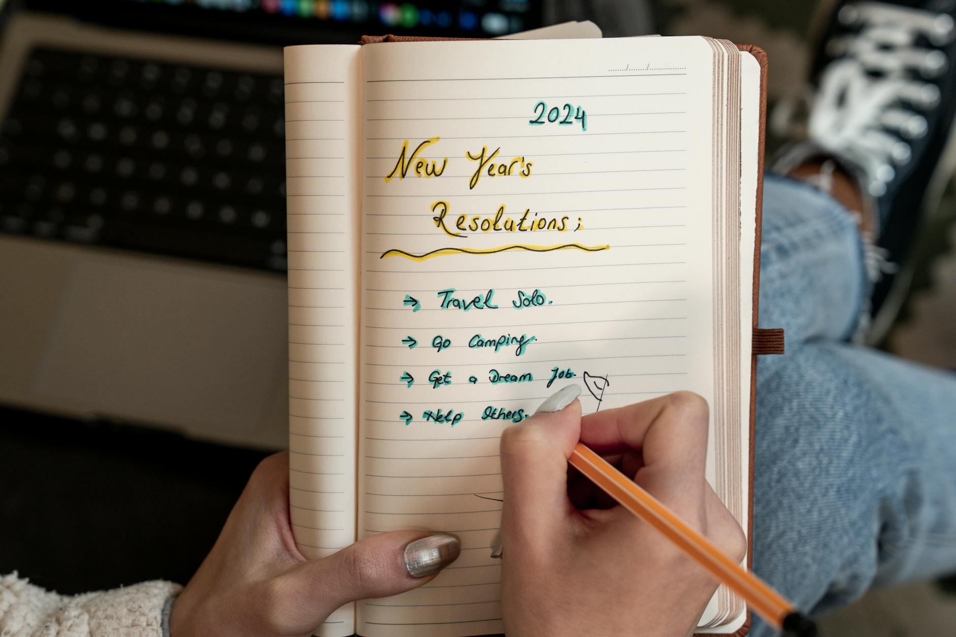 A person writes 2024 New Year's resolutions in a notebook. Concept of planning and personal goals. - what is a resolution