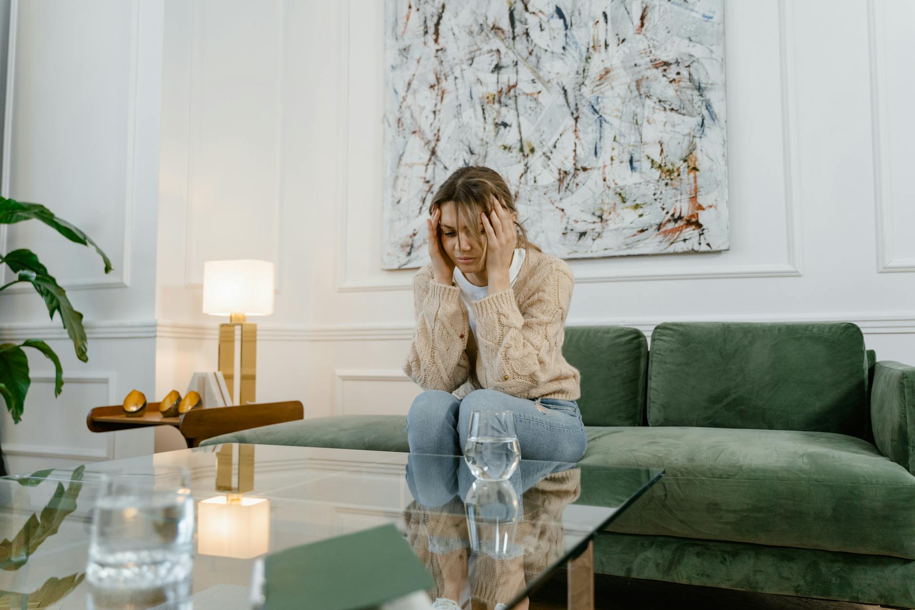 A woman sitting on a sofa at home, appearing distressed and stressed, in a modern living room. - sad treatment options