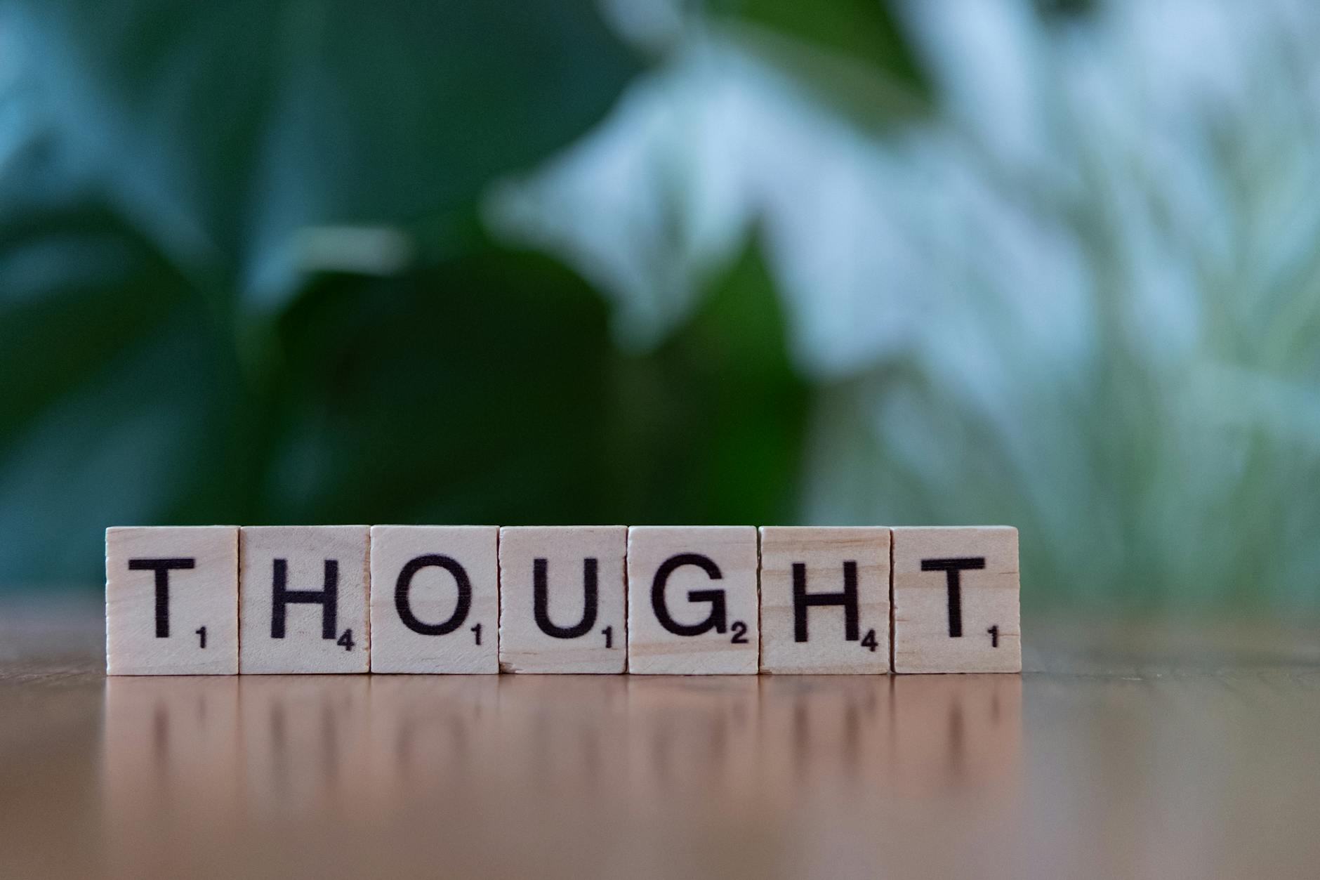 Wooden blocks spelling 'THOUGHT' on a table with a blurred background, conveying ideas and introspection. - stop overthinking
