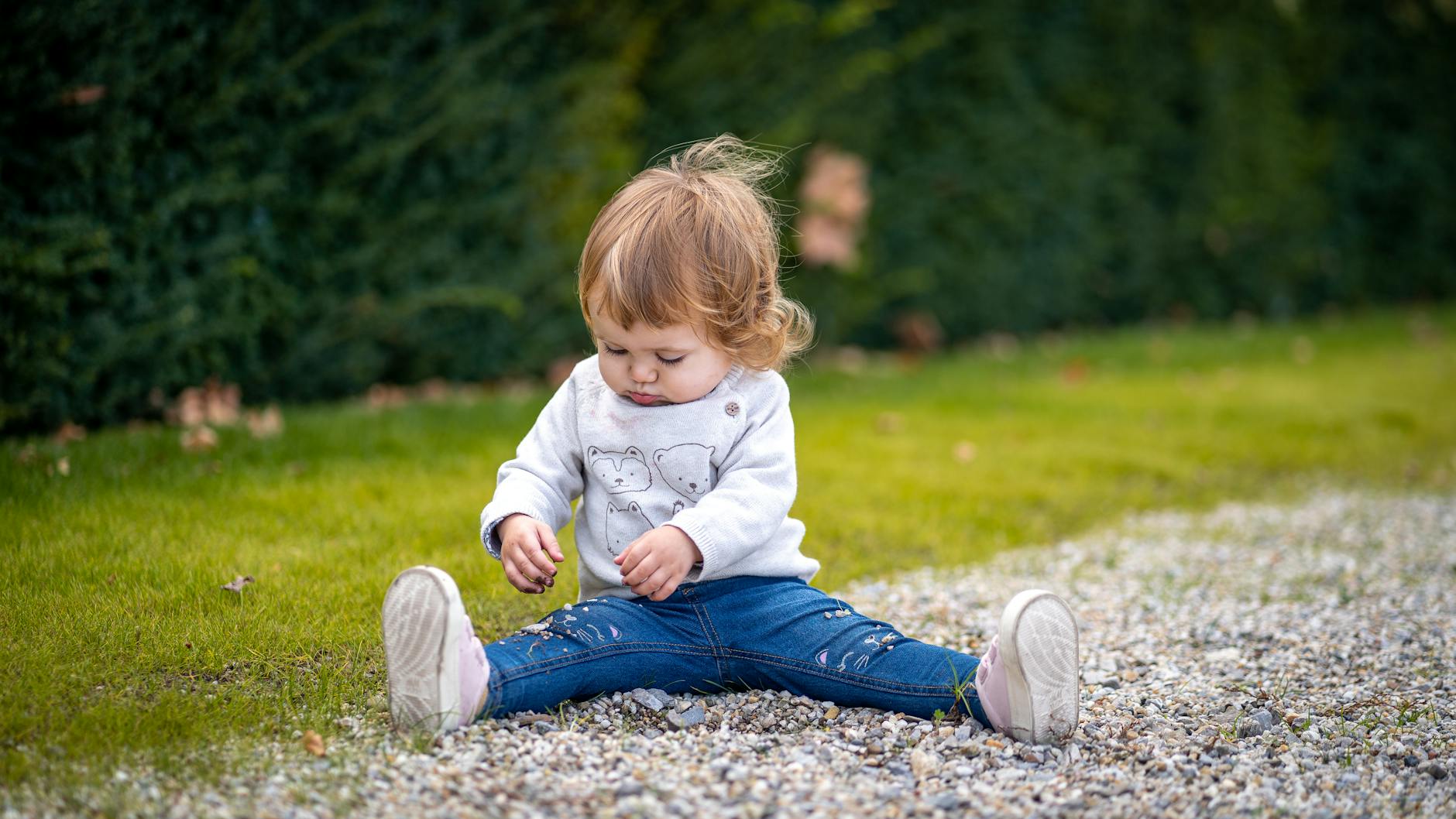 A cute toddler sitting on grass in Vienna enjoying playtime outdoors, showcasing childhood joy. - toddler growth spurts