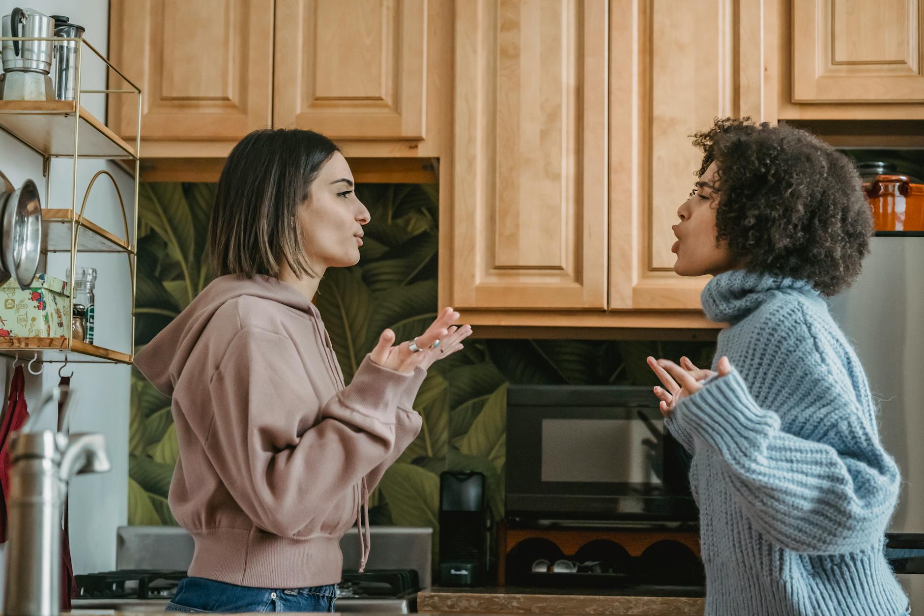 Side view of unhappy young multiracial girlfriends in casual clothes standing in kitchen while having disagreement and looking at each other - conflict resolution worksheet
