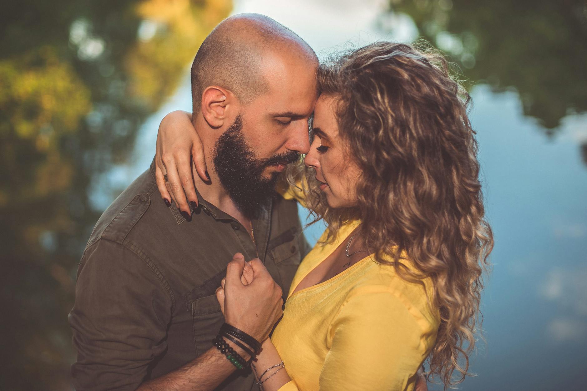 A loving couple shares an intimate moment by a serene lake, surrounded by nature's beauty. - deep couple communication
