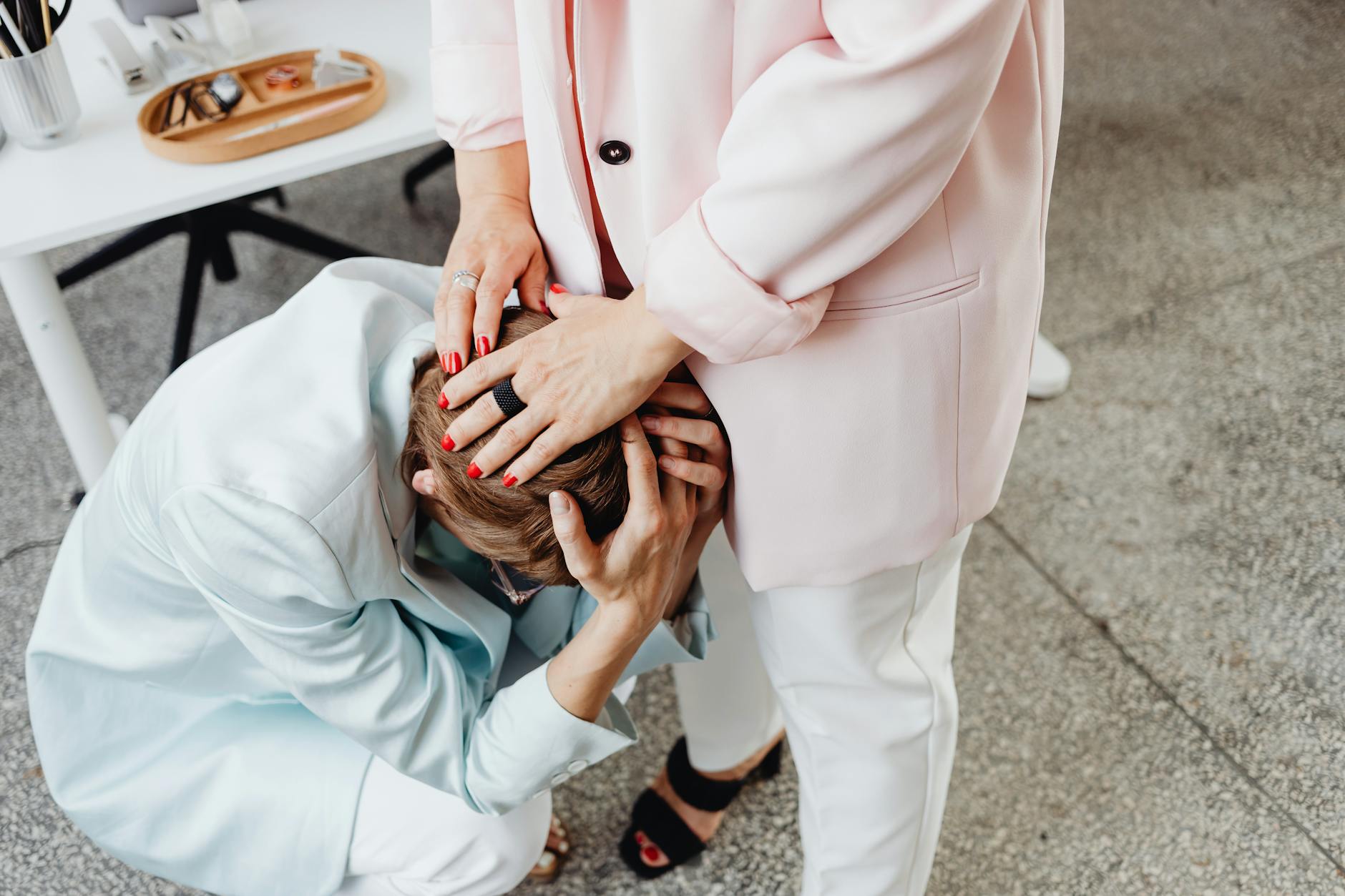 Two women in business attire providing emotional support indoors. - emotional organization