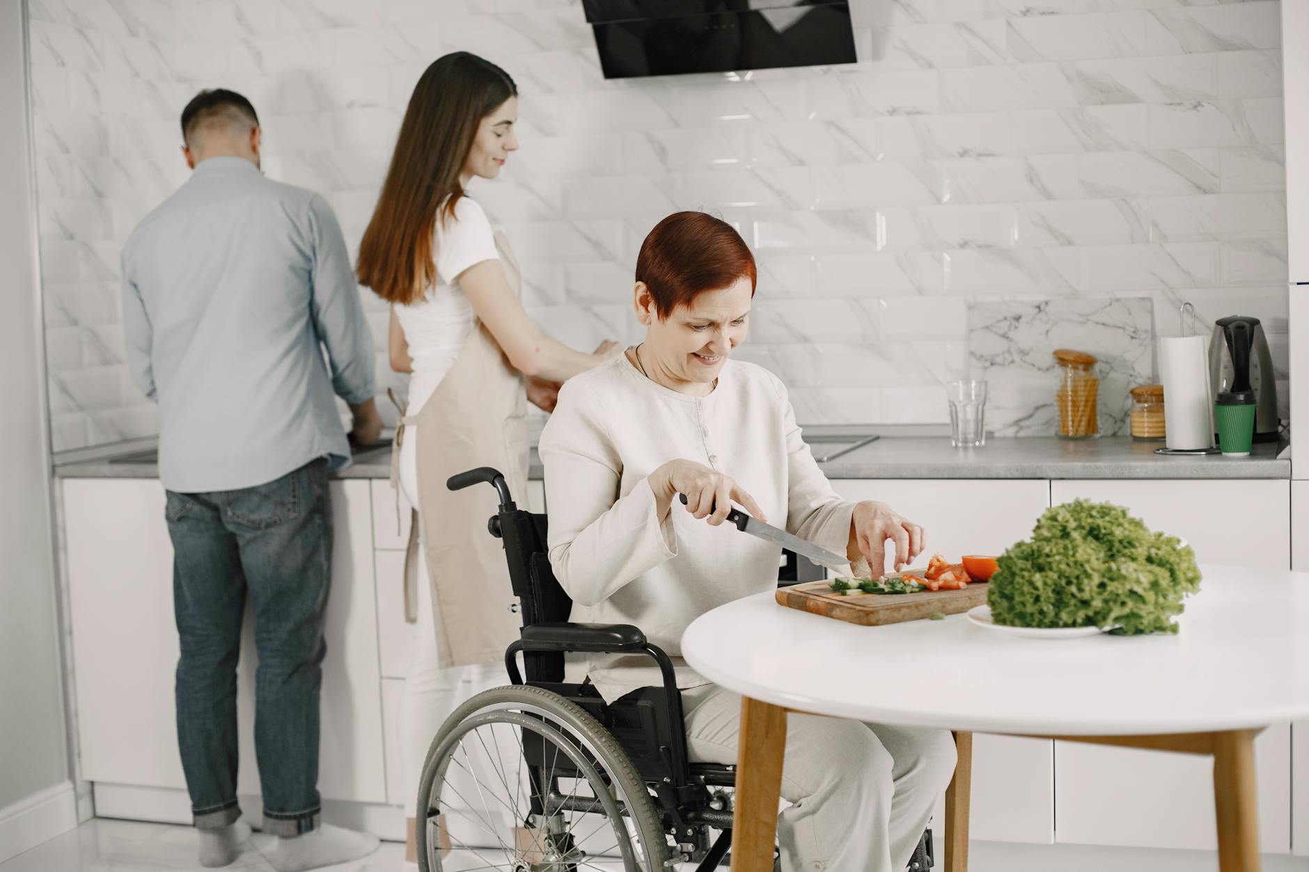 Three adults preparing vegetables in a modern kitchen, promoting inclusivity and teamwork. - express needs at home