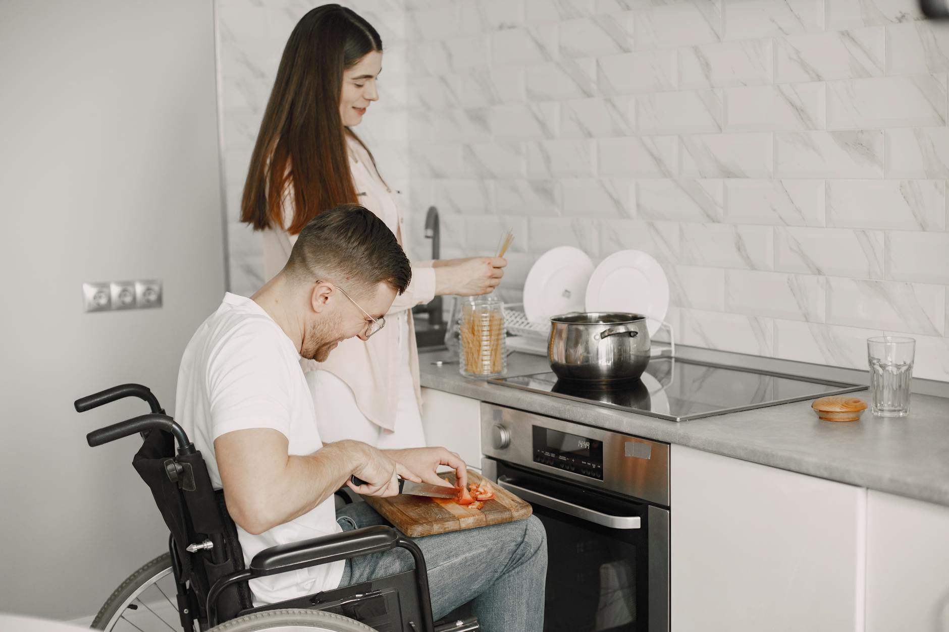 Man in wheelchair and woman cooking together in a stylish kitchen setting. - express needs at home