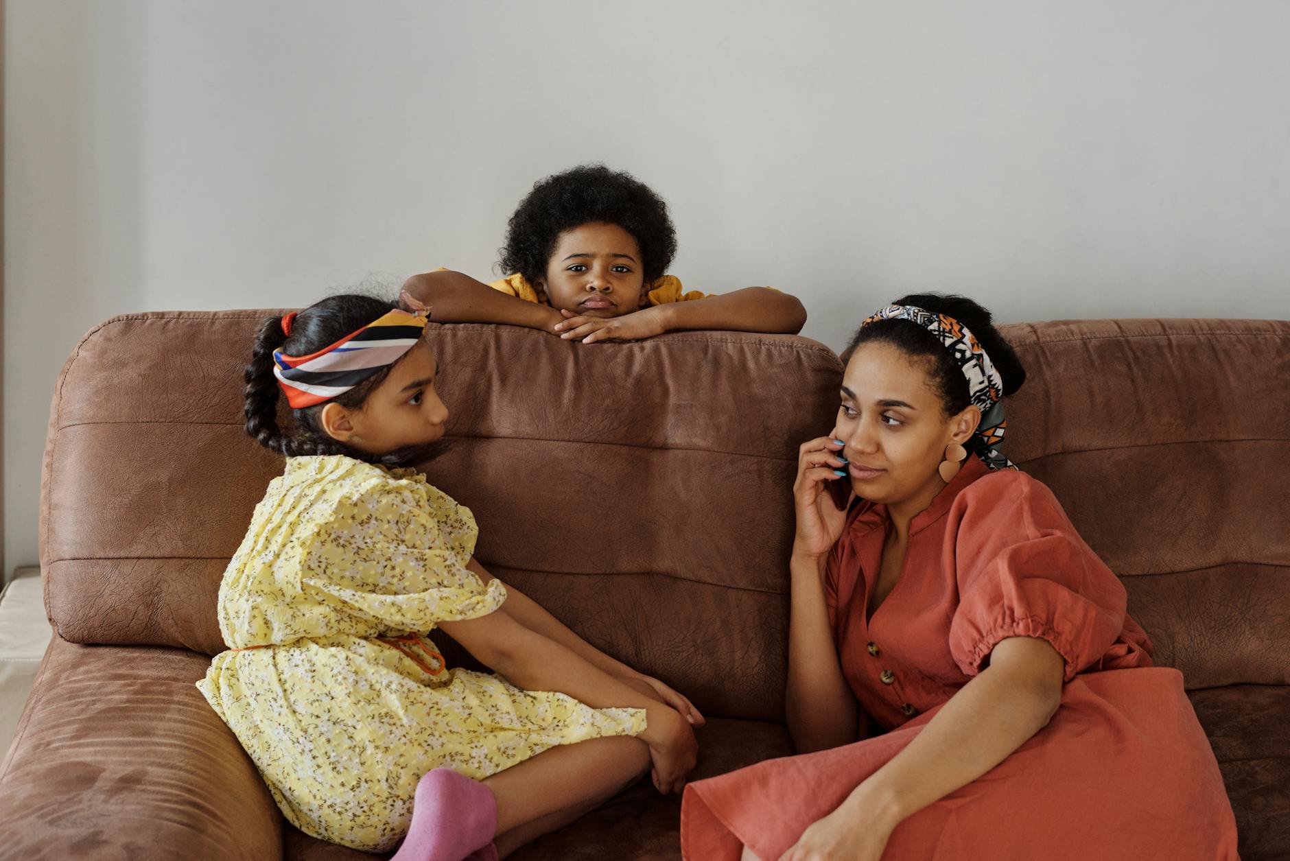 Mother and children sitting on a couch at home. Relaxed family moment indoors. - family communication tips