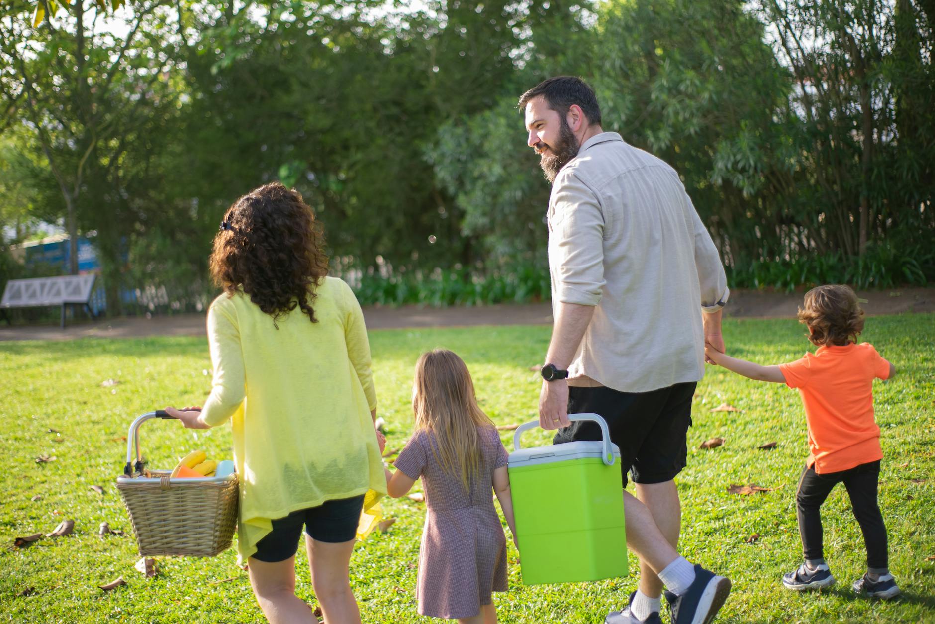 A family of four enjoys a picnic in a sunny park, capturing a joyful day outdoors. - family summer plans