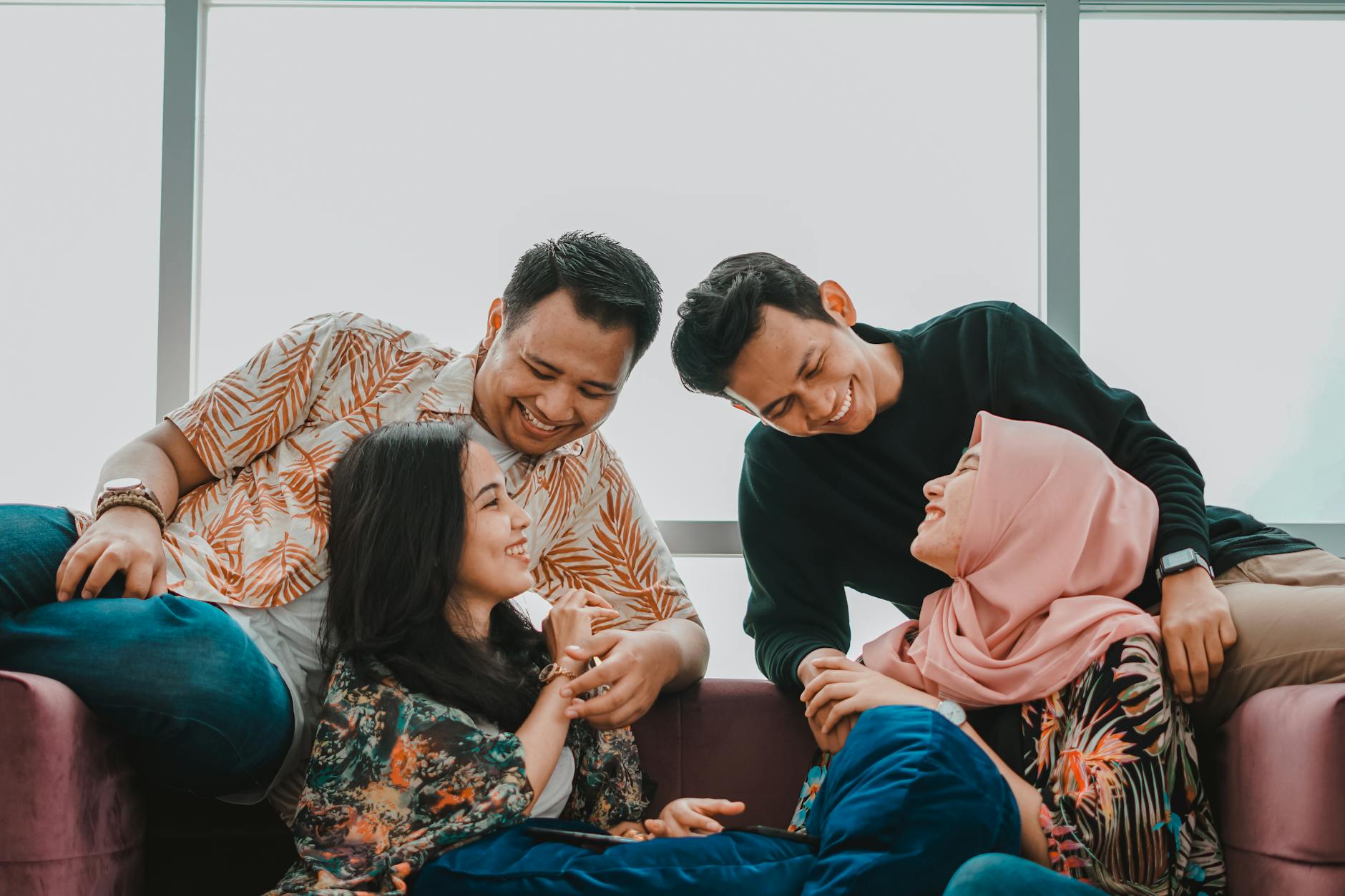 Four friends enjoy a relaxed and joyful moment indoors, sharing laughter and companionship. - friends to lovers