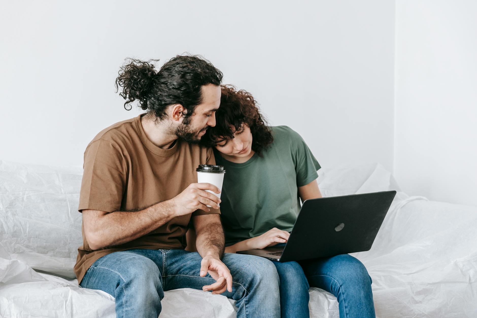 A loving couple sits on a sofa, enjoying coffee and browsing on a laptop. Perfect for lifestyle themes. - improve relationship communication