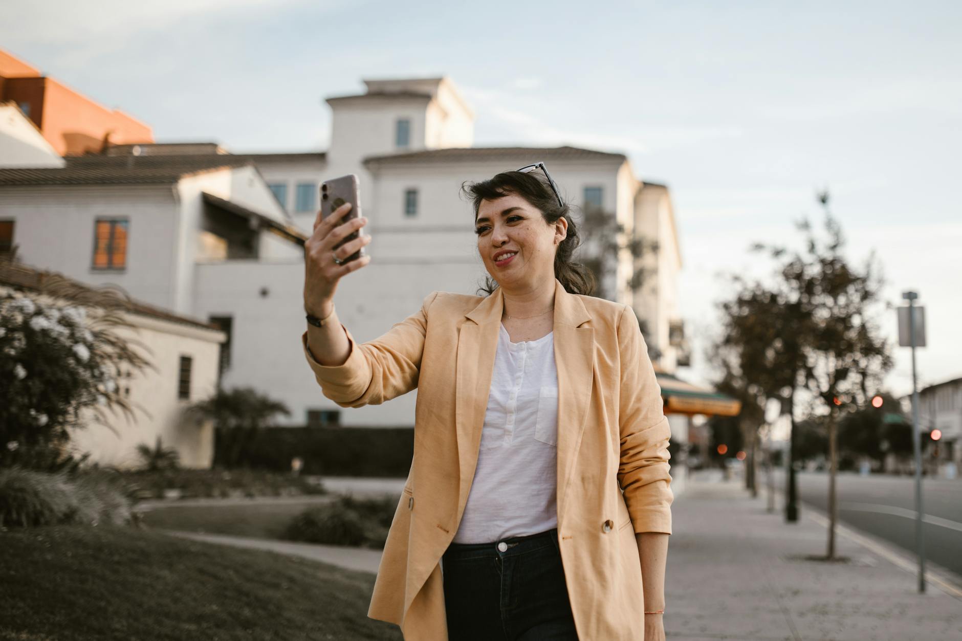 Smiling woman on a video call outdoors, showcasing modern urban lifestyle. - long distance summer