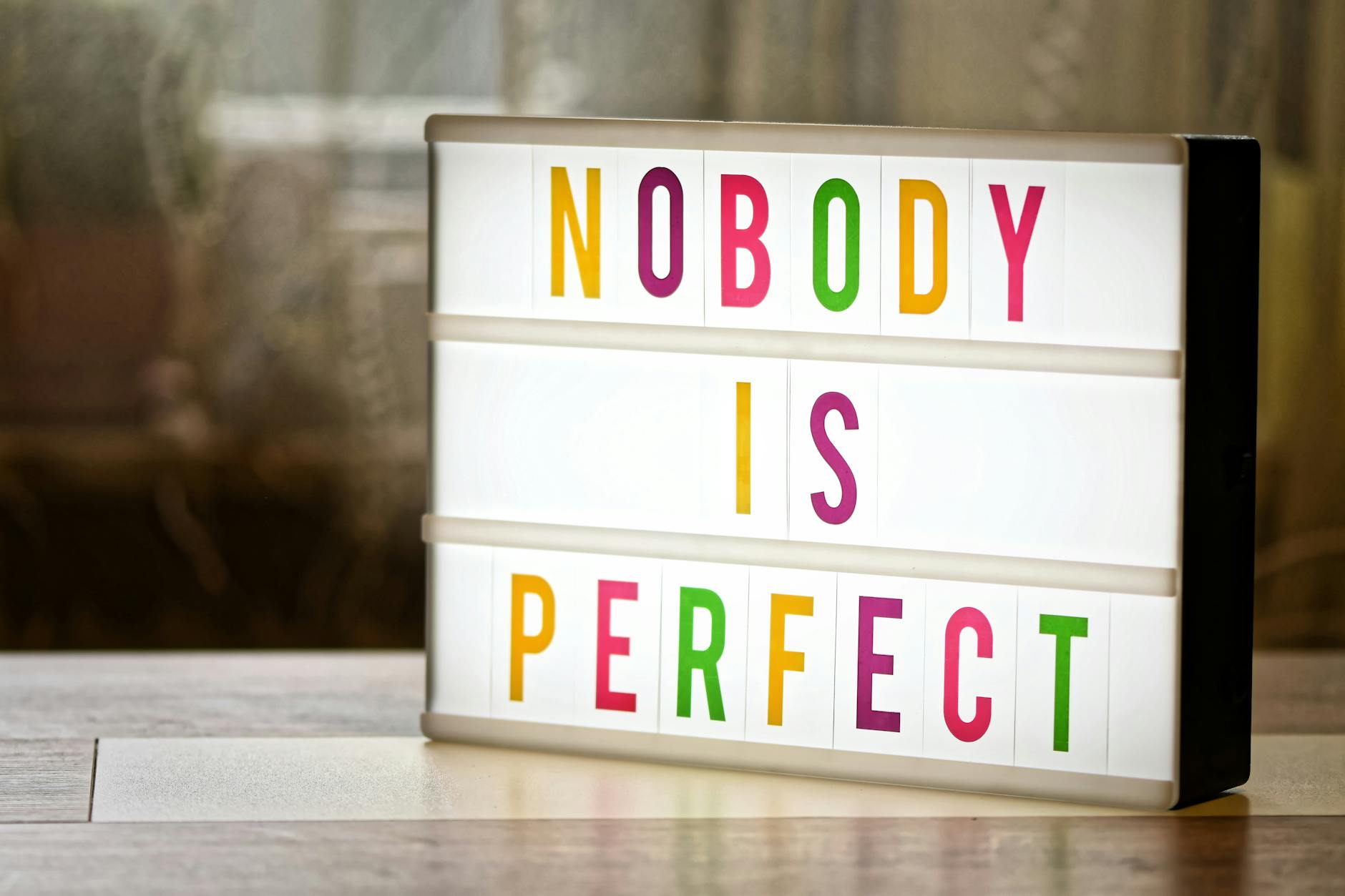 Illuminated lightbox displaying the motivational slogan 'Nobody is Perfect'. - overcome perfectionism