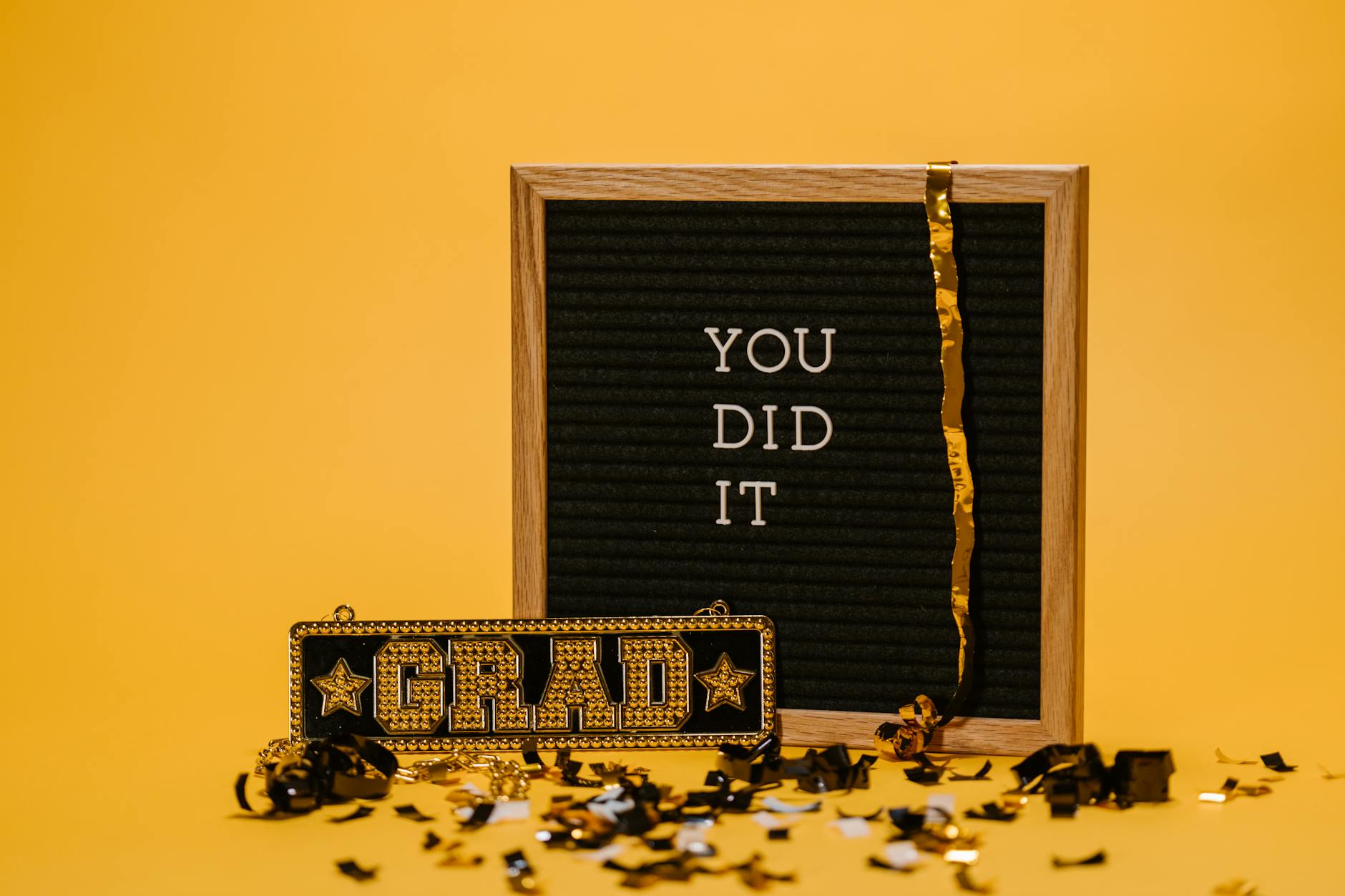 A graduation celebration with a letter board and confetti on a vibrant yellow background. - post grad relationships