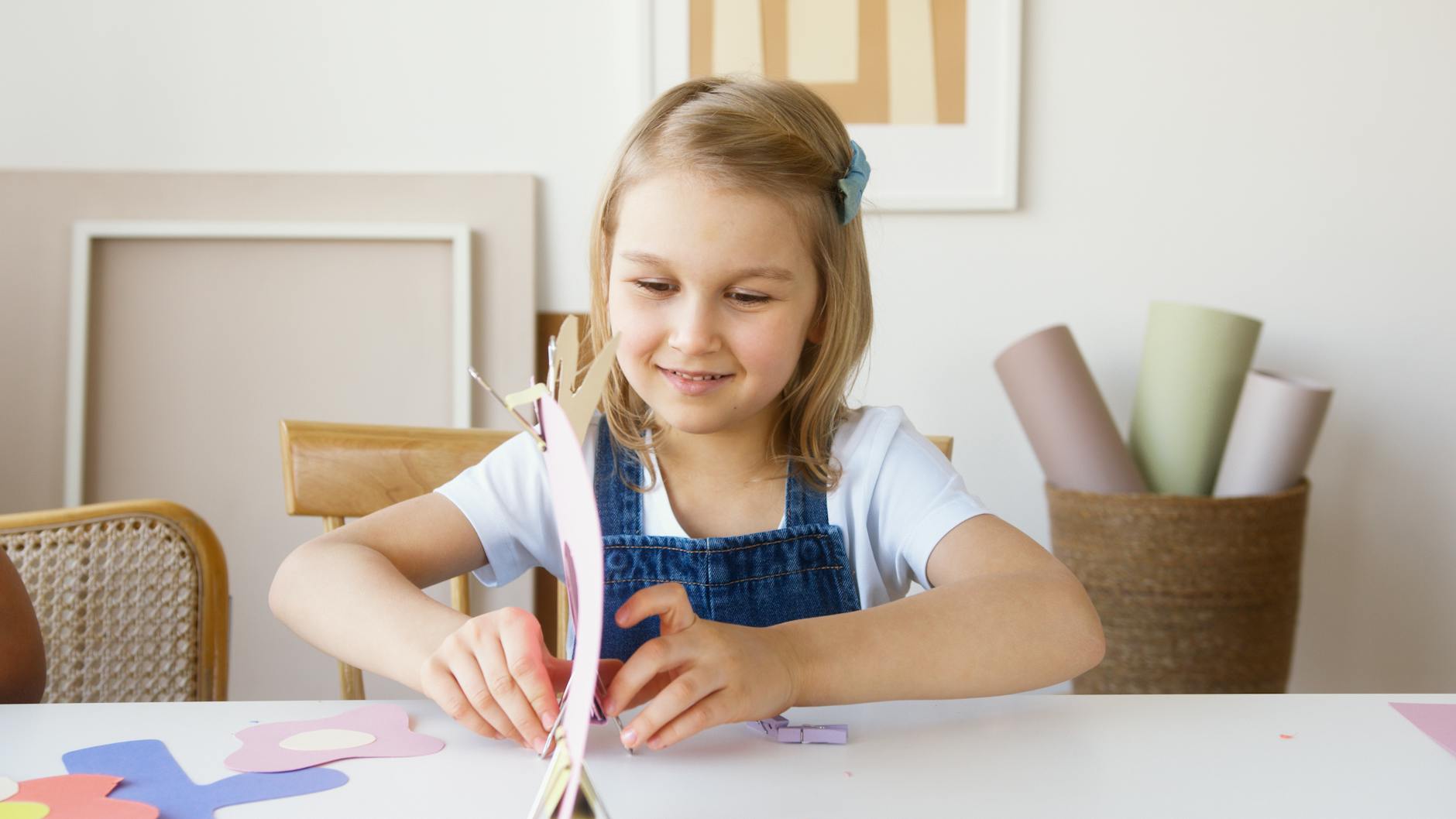 Young girl enjoying arts and crafts indoors, surrounded by colorful paper and art supplies, expressing creativity. - preschool spring crafts
