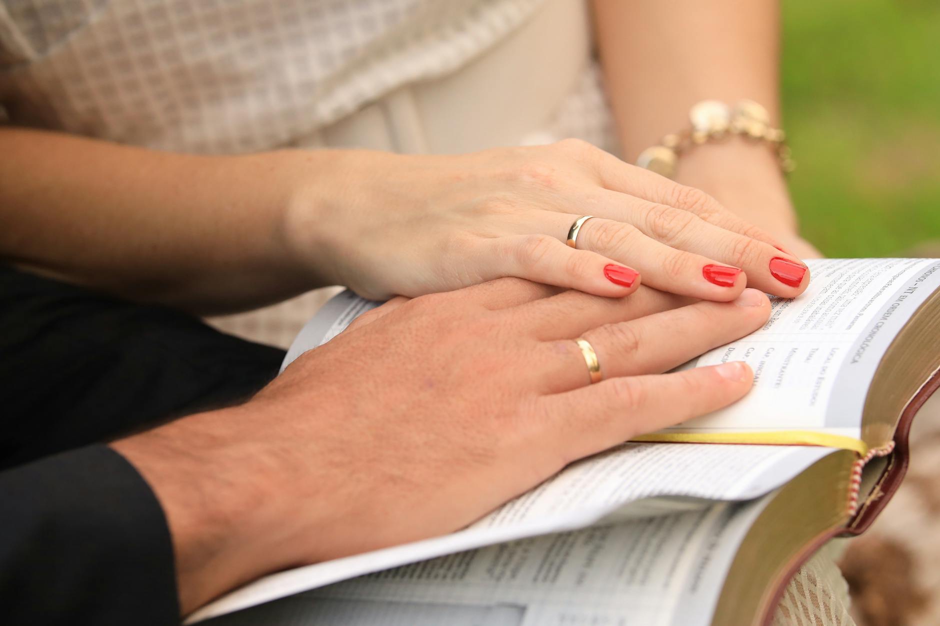Close-up of a couple with wedding rings, hands resting on an open Bible, symbolizing love and faith. - rekindle marriage connection