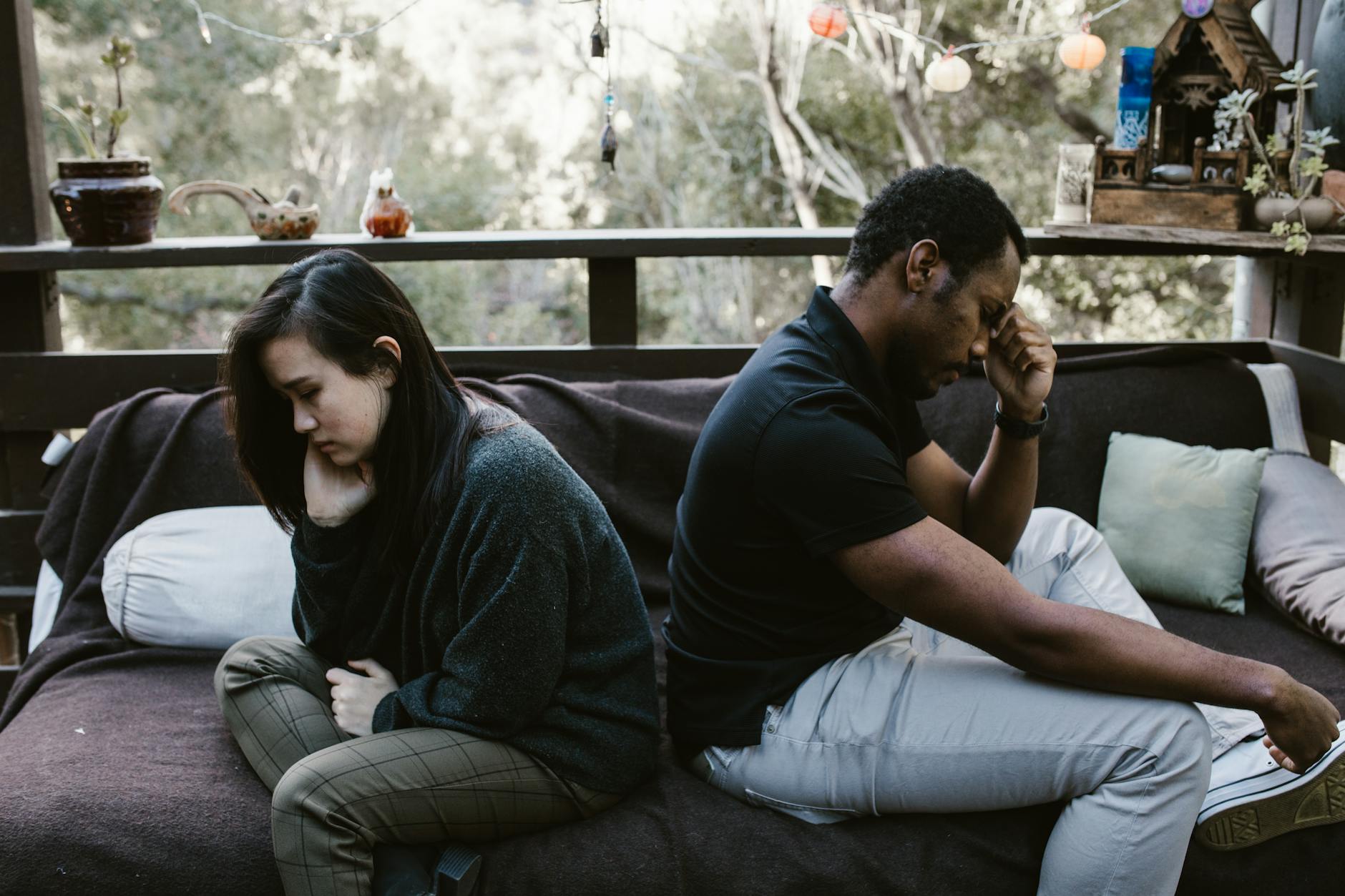 Interracial couple sitting back to back, reflecting emotional conflict, outdoors. - relationship conflict spring