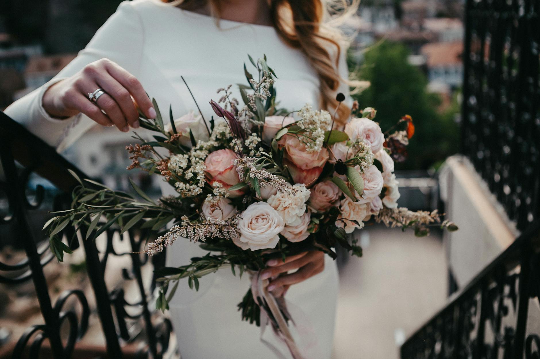 Bride holding a chic bouquet of pink and white roses, perfect for weddings. - spring wedding survival