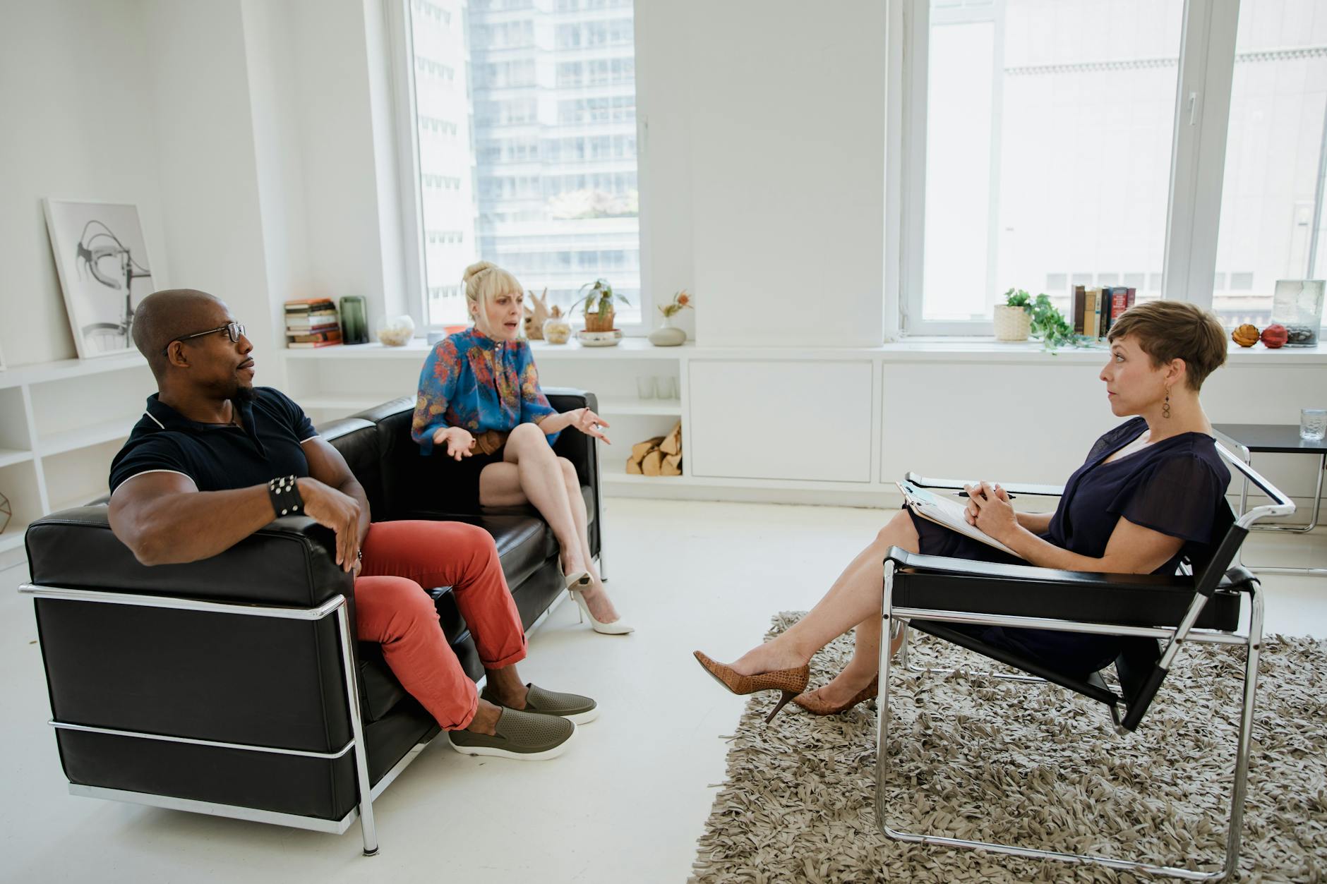 A couple in a counseling session with a therapist in a modern office setting. - therapist for relationship anxiety