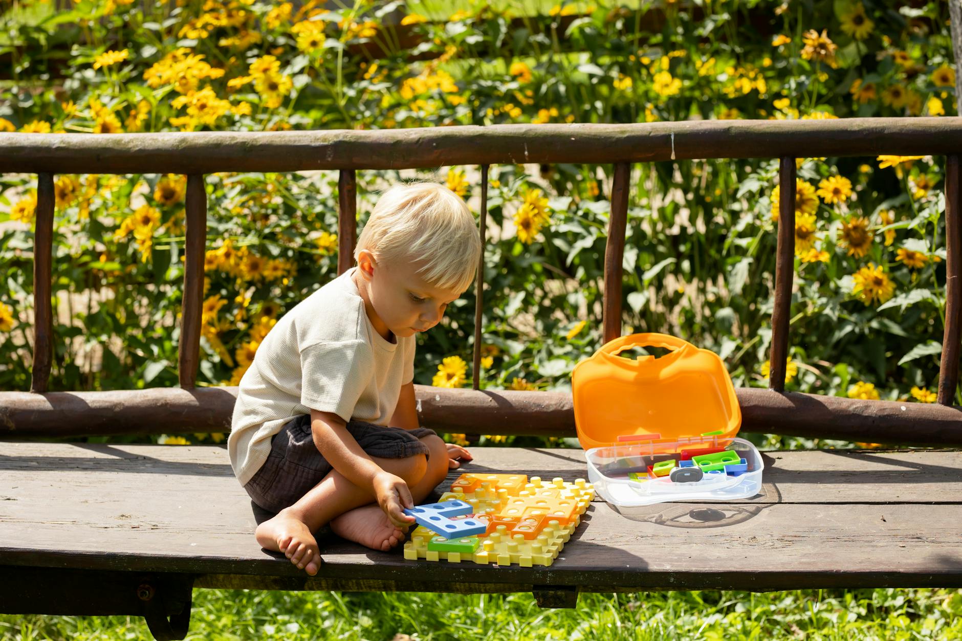 A young boy playing with a colorful puzzle outdoors on a sunny summer day. - toddler sleepaway camp