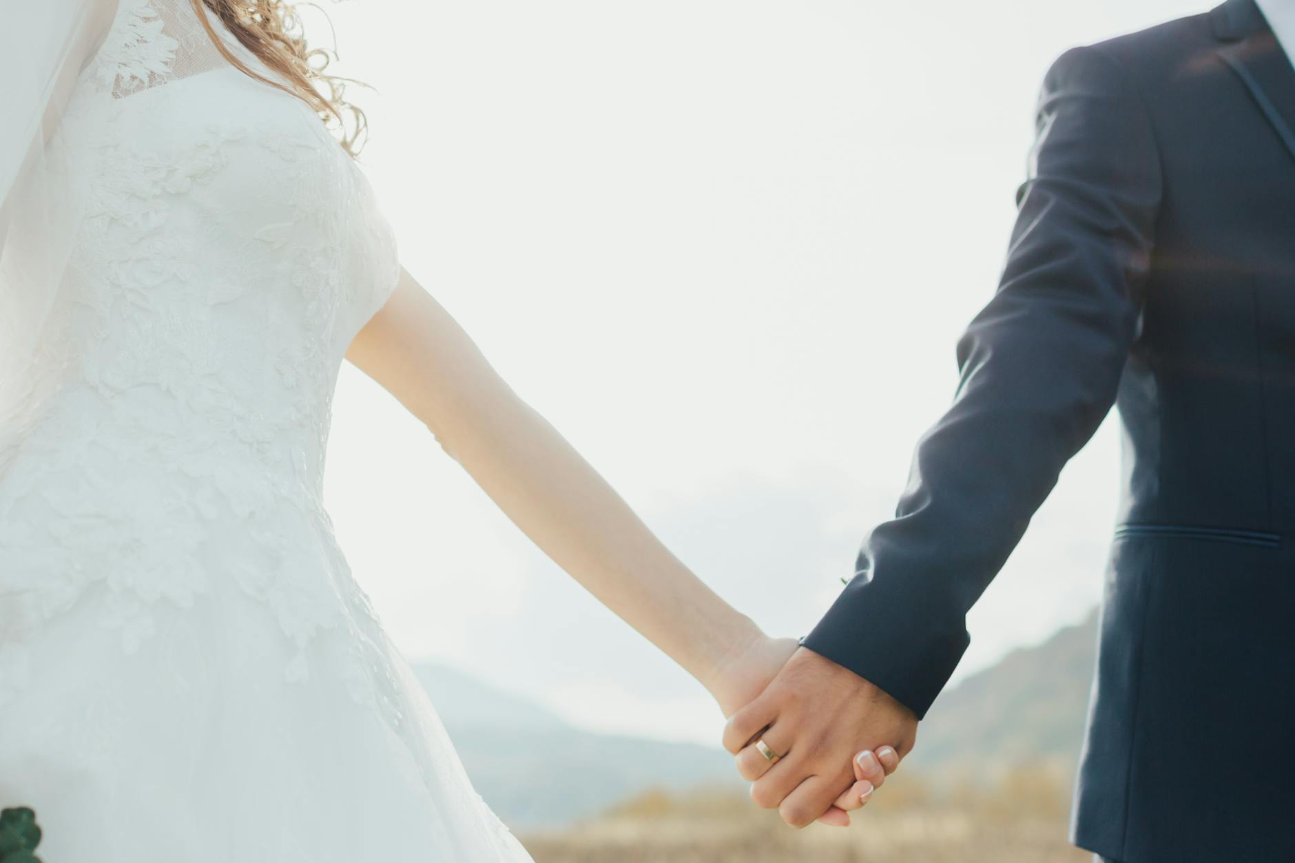 Bride and groom holding hands in a romantic outdoor setting, symbolizing love and unity. - wedding stress management